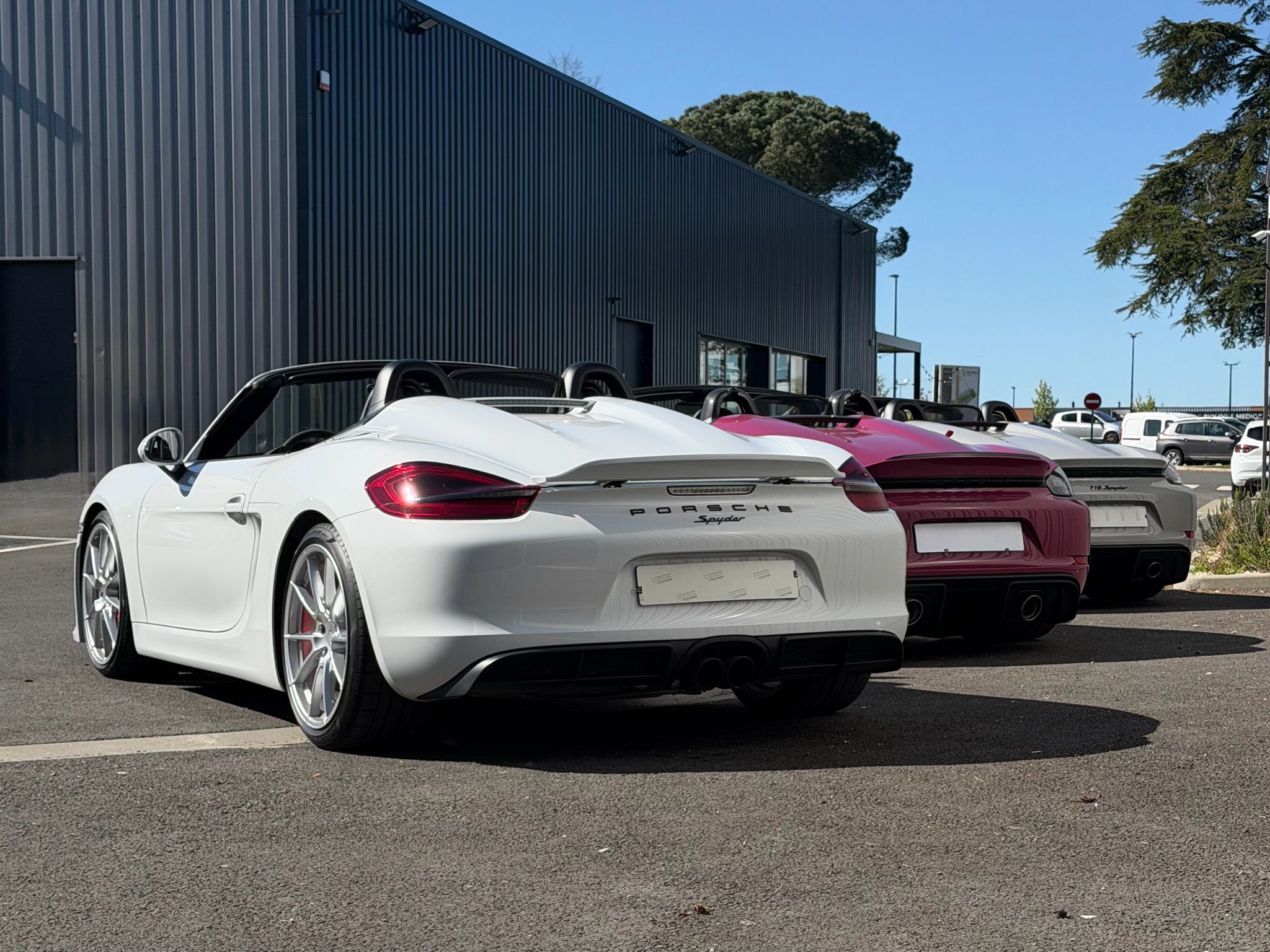 Trois Porsche Boxster Spyder devant le showroom Sportivo